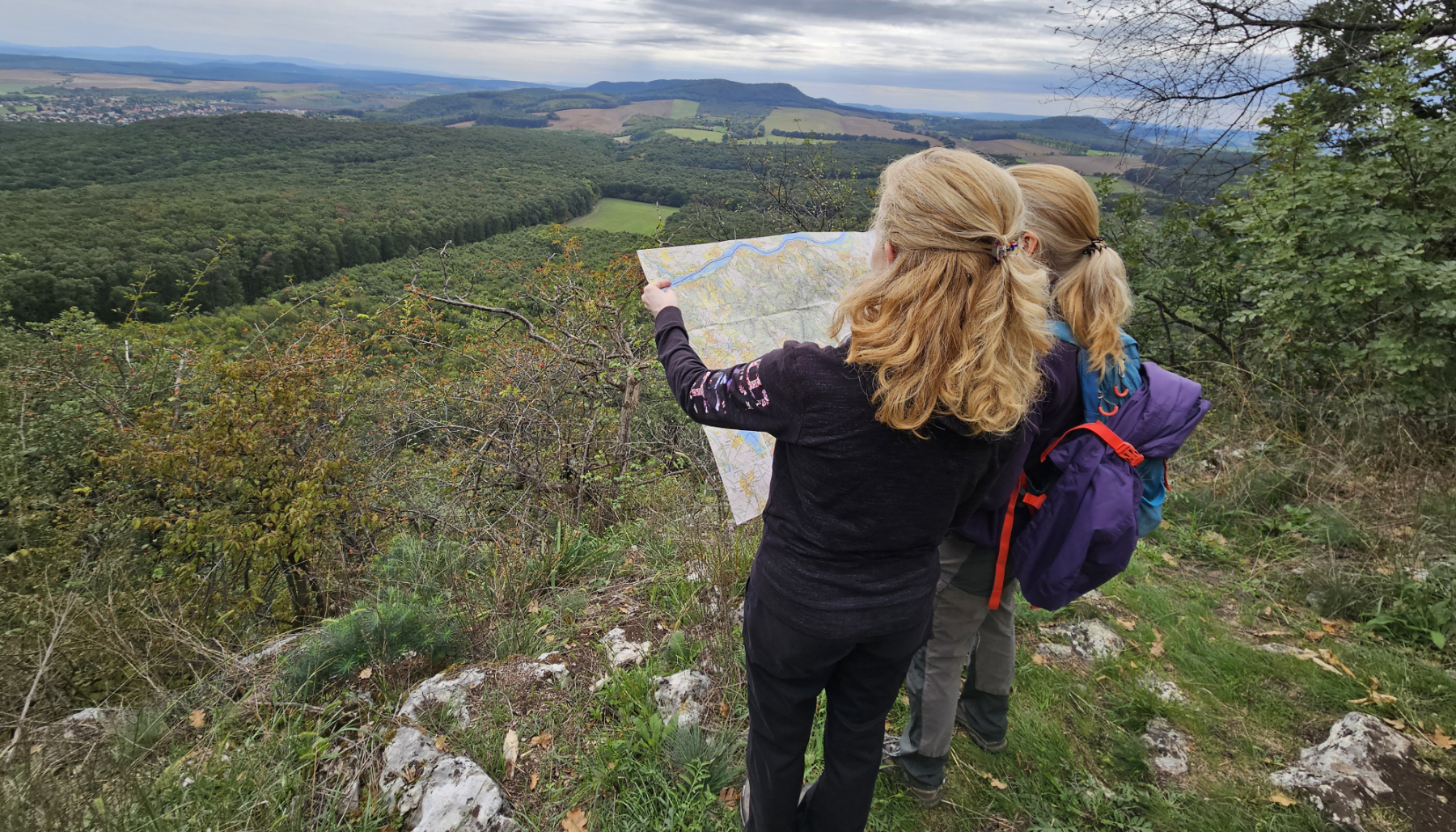a Gerecsében állva, a fantasztikus kilátással együtt a térképet is bogarássza Eszti és Zsóki
