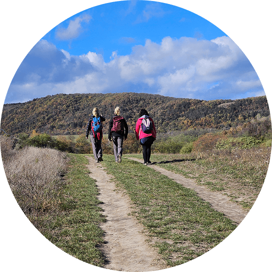 három túrázó nyílt terepen, a háttérben hegyvonulat