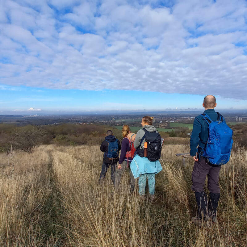 Turisták haladnak egy mezőn, messzire ellátni.
