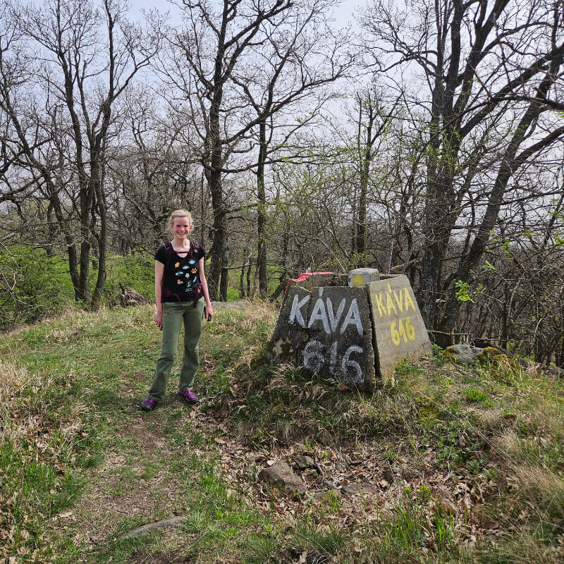 A Káva csúcsán lévő háromszögelési pont, mellette egy vidám turistával.