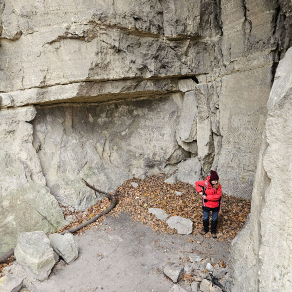 Az Országház-kőfejtő egyik fala, előtte egy turistával.