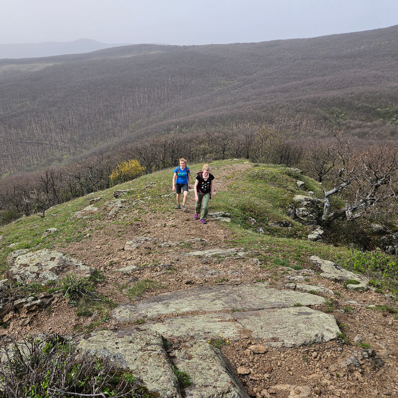Turisták közelednek a Világos-vár csúcsa felé, a háttérben hegyek.